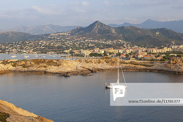 Ein Segelboot auf dem klaren Meer um das Dorf Ile Rousse bei Sonnenuntergang  Region Balagne  Korsika  Frankreich  Mittelmeer  Europa