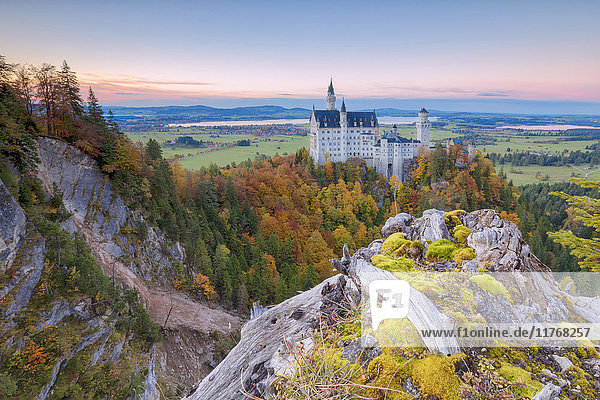 Sonnenuntergang auf Schloss Neuschwanstein umgeben von bunten Wäldern im Herbst  Füssen  Bayern  Deutschland  Europa