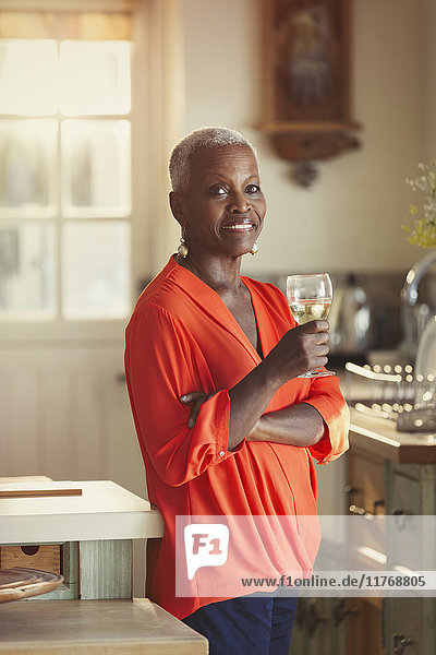 Portrait lächelnde Seniorin beim Weintrinken in der Küche