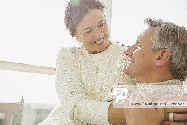 Affectionate mature couple hugging on sunny porch