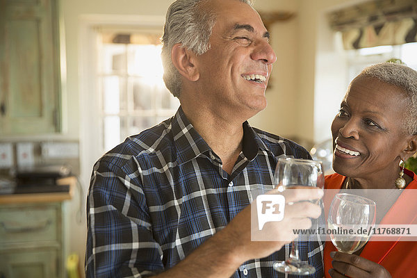 Lachendes Seniorenpaar trinkt Weißwein
