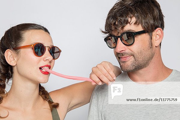 Mid-adult couple wearing sunglasses  she is eating candy