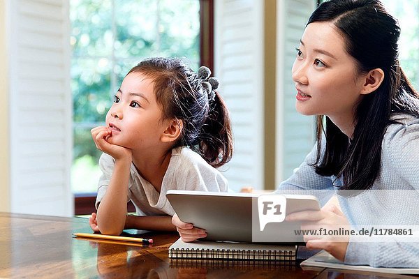 Mother and daughter using digital tablet at home