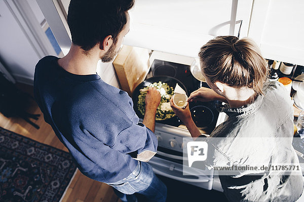 Hochwinkelansicht von Mann und Frau beim Kochen von Nudeln in der Küche zu Hause