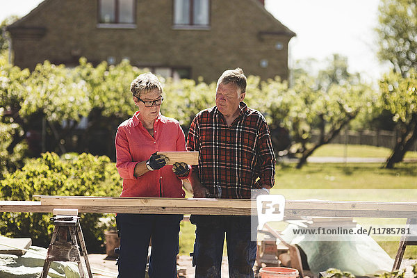Seniorenpaar beim Betrachten von Holzbrettern auf dem Hof