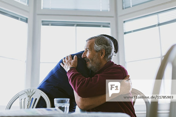 Hausmeister umarmt den älteren Mann zu Hause