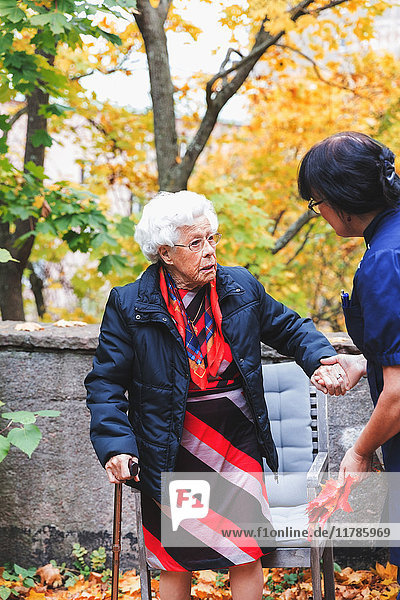 Hausmeisterin assistiert Seniorin im Park
