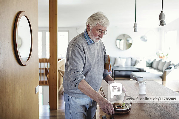 Senior man holding breakfast in tray at home