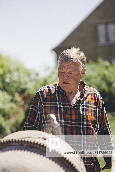 Senior Mann schaut auf Zementmischer auf dem Hof