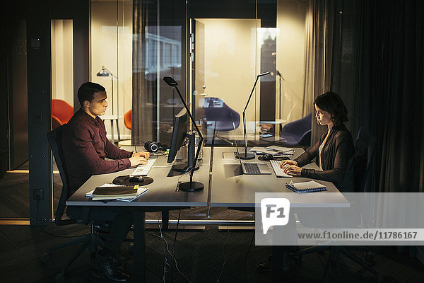 Side view of business colleagues working at desk in dark office
