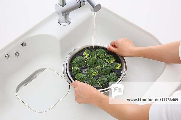 Japanese woman washing broccoli in the kitchen