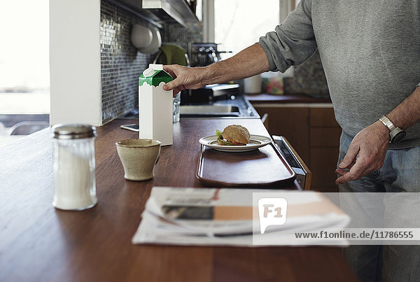 Midsection of senior man preparing breakfast at kitchen counter