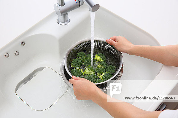 Japanerin wäscht Brokkoli in der Küche