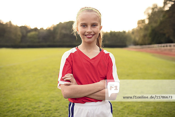 Porträt einer glücklichen Athletin mit gekreuzten Armen auf dem Fußballfeld