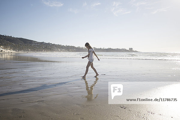 Ganzflächige Seitenansicht des Mädchens  das an einem sonnigen Tag am Strand spazieren geht.