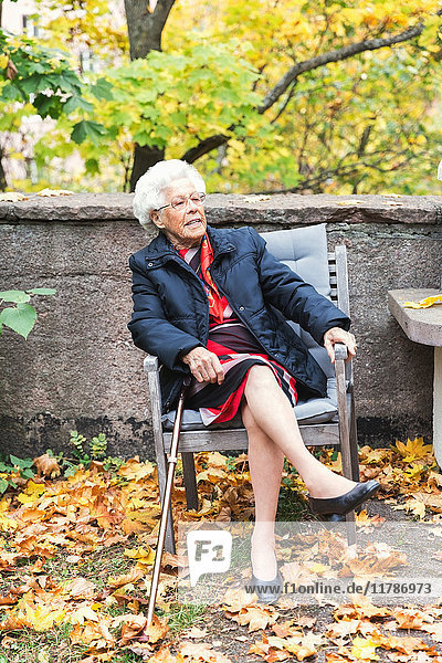 Full length of senior woman sitting on chair in park