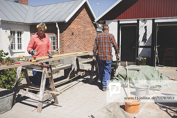 Senior couple doing carpentry at yard outside house