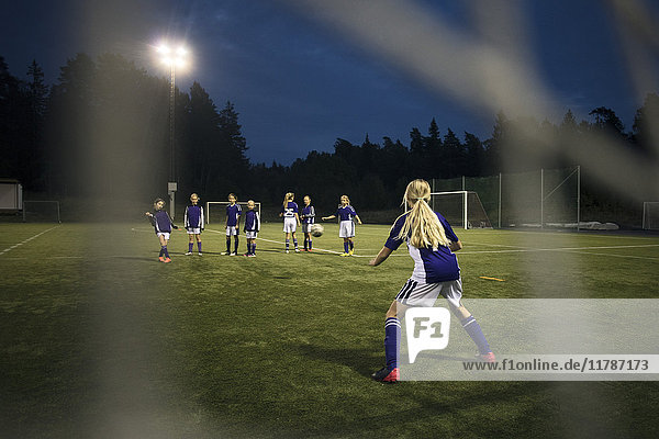 Mädchen beim Fußballspielen vom Torpfosten-Netz auf dem Feld gegen den Himmel gesehen
