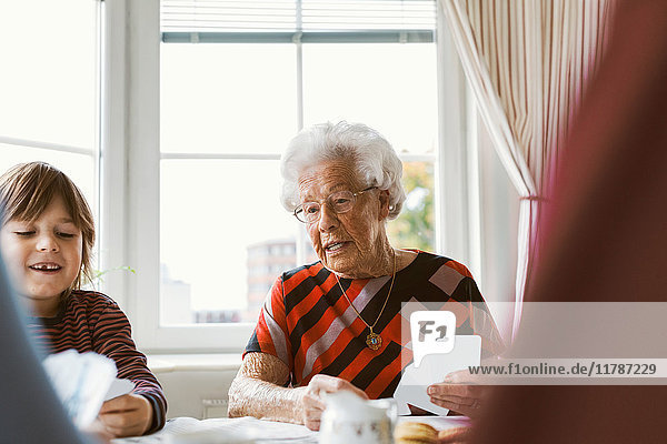 Senior woman playing cards with family at home