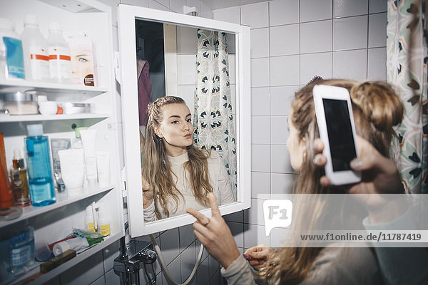 Abgeschnittene Hand einer Frau  die eine Freundin in Spiegelreflexion im Schlafsaal fotografiert.