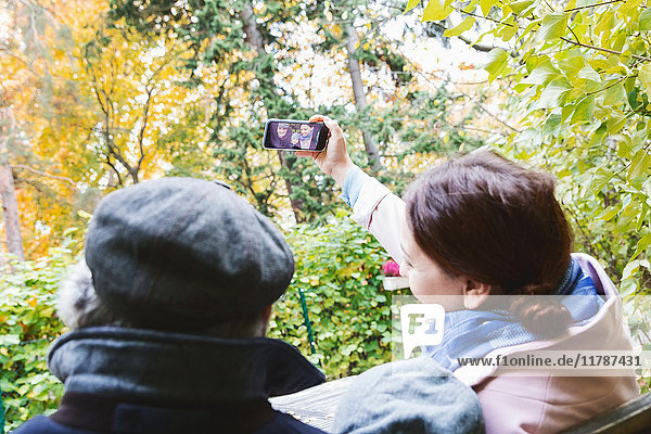 Frau nimmt Selfie durch Smartphone mit Familie im Park im Herbst