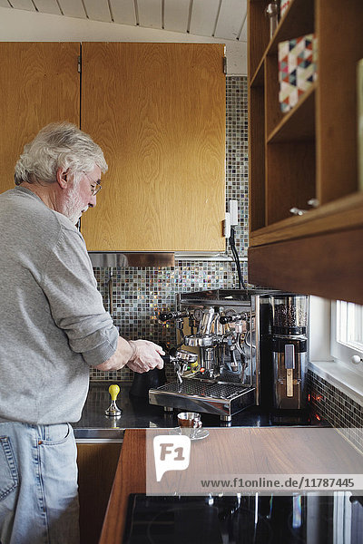 Senior Mann mit Kaffeemaschine auf der Küchenzeile zu Hause