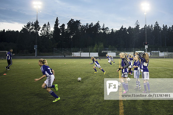 Mädchen spielen Fußball auf dem Feld gegen den Himmel