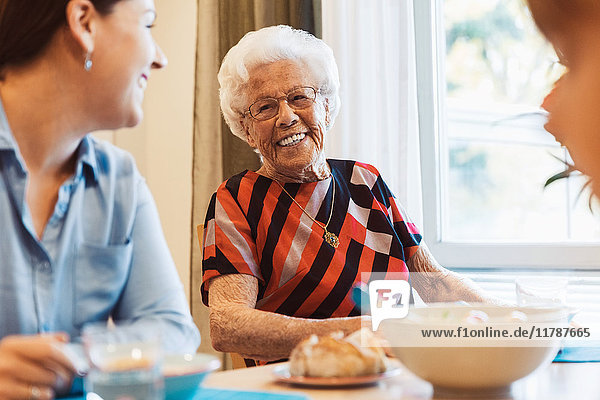 Happy senior woman talking to daughter at dining table