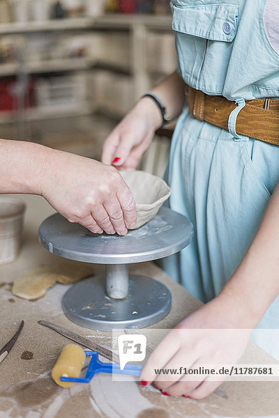 Abgeschnittene Hand der weiblichen Töpferform auf Ton auf Metall von junger Künstlerin in der Werkstatt