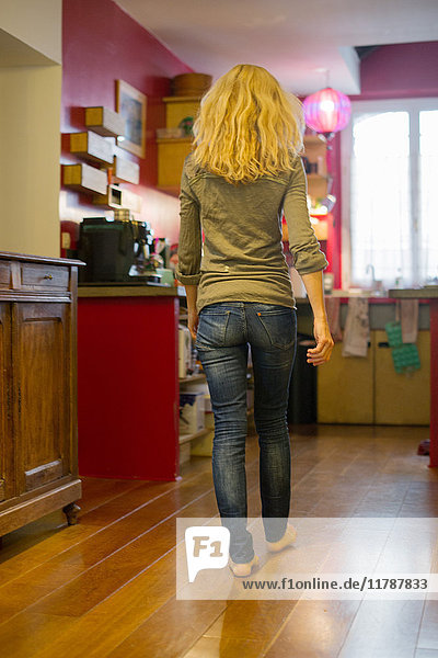Woman walking toward kitchen at home  rear view