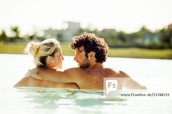 Paare die sich im Wasser entspannen und sich gegenseitig in die Augen schauen.