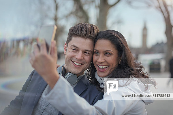Lächelndes Paar nimmt Selfie mit Fotohandy im Stadtpark auf