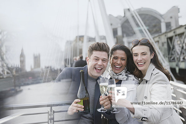 Portrait enthusiastic business people celebrating  toasting champagne on urban bridge  London  UK