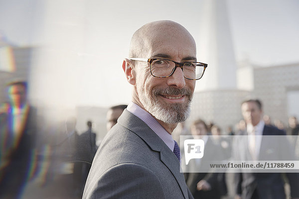 Portrait lächelnder  selbstbewusster Geschäftsmann auf belebten Bürgersteigen  London  UK