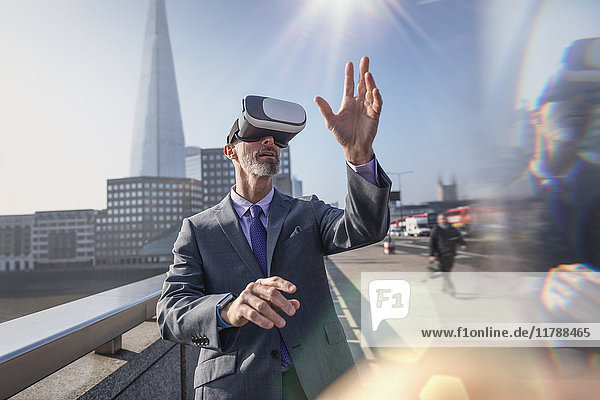 Geschäftsmann mit Virtual-Reality-Simulator-Brille auf sonniger Stadtbrücke  London  UK
