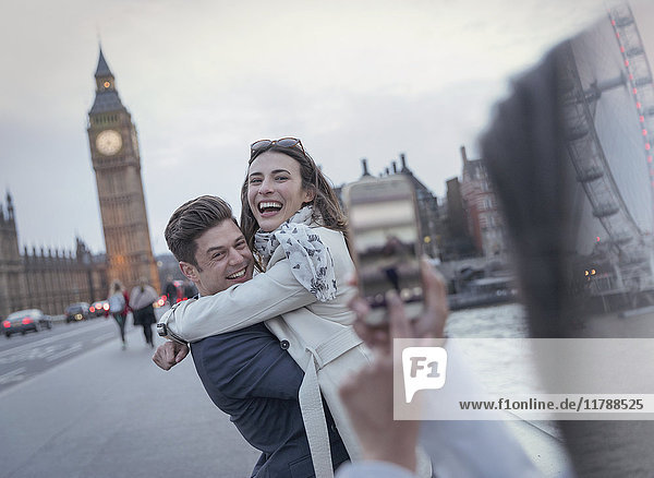 Playful couple tourists being photographed on bridge near Big Ben  London  UK