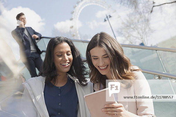 Smiling businesswomen using digital tablet outdoors