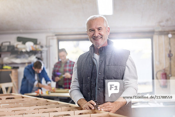 Portrait lächelnder Schreiner bei der Arbeit auf dem Holzboot in der Werkstatt