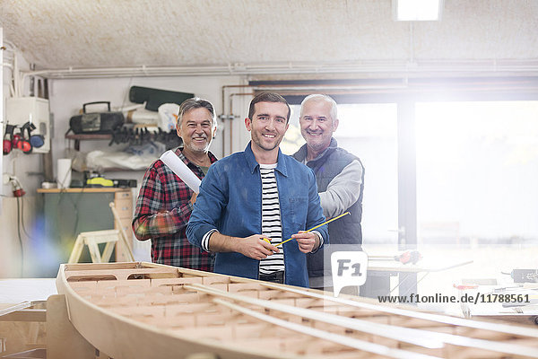 Portrait lächelnde Schreiner bei der Arbeit am Holzboot in der Werkstatt