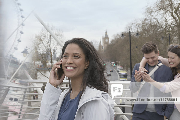 Lächelnde Frau beim Telefonieren auf der urbanen Brücke  London  UK