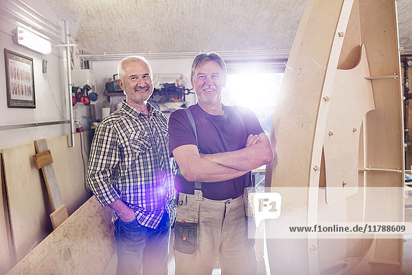 Portrait lächelnde Schreiner  die in der Werkstatt Holzboote herstellen.