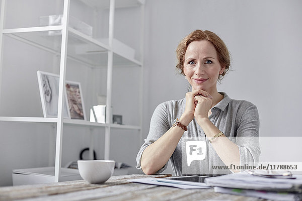 Portrait lächelnde  selbstbewusste Geschäftsfrau mit digitalem Tablett und Tee trinken im Büro
