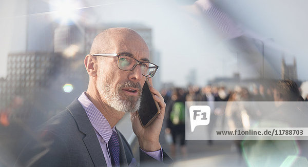 Seriöser Geschäftsmann im Gespräch auf dem Handy in der belebten Stadtstraße
