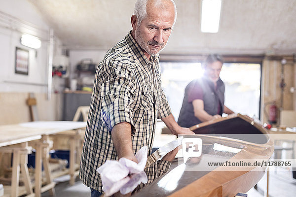 Senior Man Finishing  Wischen Holz Kajak in der Werkstatt