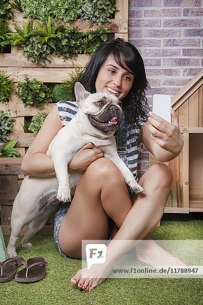 Frau und französische Bulldogge mit einem Selfie auf der Terrasse