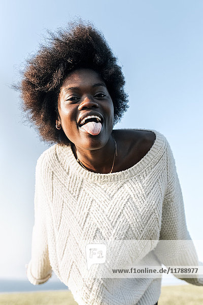 Porträt einer jungen Frau  die ihre Zunge herausstreckt.