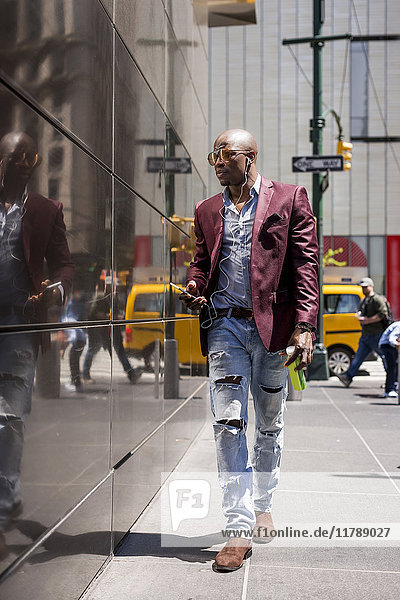 USA  New York City  Manhattan  stylish businessman listening music with headphones and smartphone
