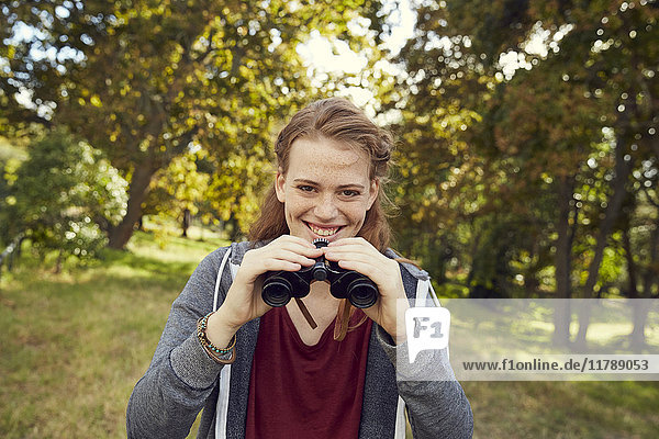 Portrait of smiling young woman using binoculars