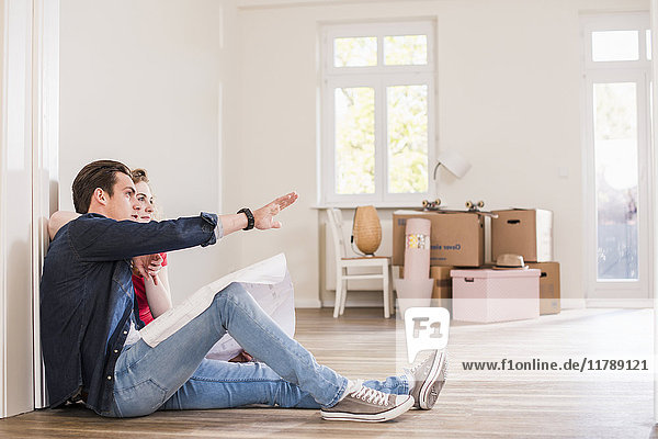 Young couple in new home sitting on floor discussing ground plan