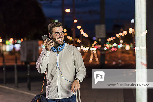 Young man in the city with headphones and cell phone at night
